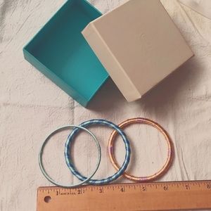 3 yarn bracelets. 1 orange/lavender, 1 green/blue, 1 mint green.